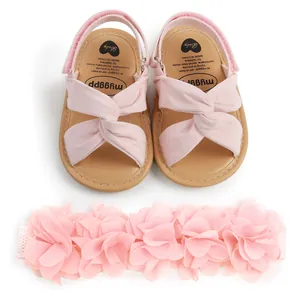 Conjunto de sandalias rosas para bebé con tiras cruzadas y diadema floral a juego.