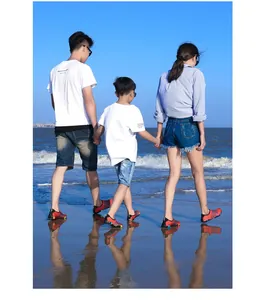 Familie wandelt op het strand met rode waterschoenen voor zwemmen en snorkelen