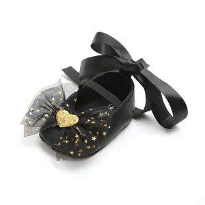 Nahaufnahme schwarzer Baby-Prinzessinenschuhe mit Schleife und Tüll mit Goldherz-Detail
