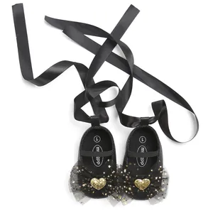 Detailansicht schwarzer Baby-Prinzessinenschuhe mit Bändern und Goldherz-Glitzer.