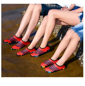 Detailopname van rood gestreepte waterschoenen gedragen op een zonnig zandstrand aan zee