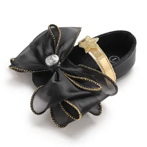 Detailed view of black baby girl princess shoe with large bow and gold star strap