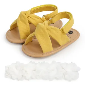 Primer plano de sandalias amarillas de bebé con tiras cruzadas y diadema floral