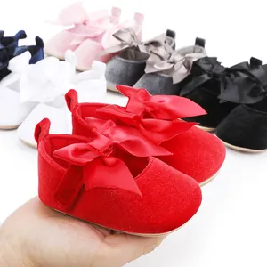 Close-up van rode fluwelen baby prinsessenschoenen met een grote satijnen strik