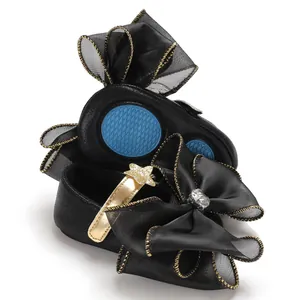 Detail view of black baby princess shoes with large mesh bow and gold strap.