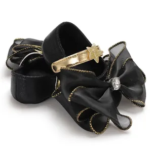 Close-up detail of black baby princess shoes with gold star and large ribbon bow