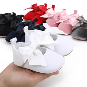 Detail van witte fluwelen baby prinsessenschoenen met een grote satijnen strik.