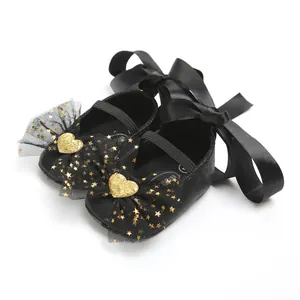 Detail von schwarzen Baby-Prinzessinenschuhen mit goldenen Sternen und Satinschleifen.