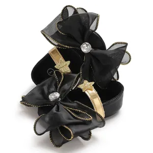Detailed view of baby princess shoes featuring large black mesh bows and gold stars