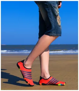 Gedetailleerd beeld van oranje waterschoenen met grijze strepen op een zonnig zandstrand