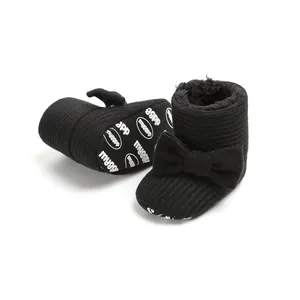 Close-up of black baby winter snow boots with warm plush lining and stylish bow decoration