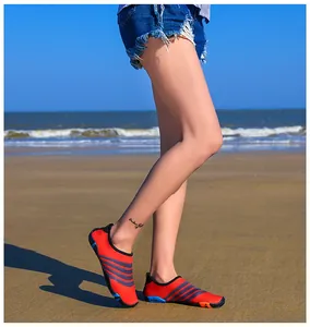Close-up van rode snorkelschoenen met antislipzolen gedragen door een model op het strand
