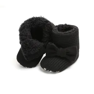 Close-up of black fleece-lined baby snow boots with bow detail and knit texture