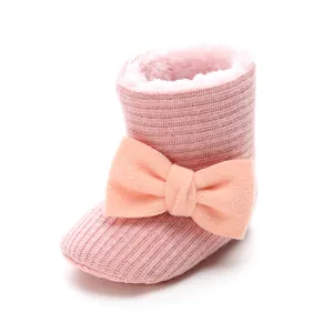 Detailed view of pink knitted fleece-lined baby boots with a large decorative bow