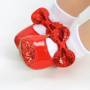 Macro view of sparkly red glitter bow on shiny patent leather baby princess shoes