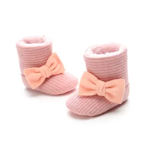 Close-up detail of pink knitted baby snow boots with warm plush lining and decorative bow