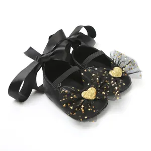 Detailansicht schwarzer Baby-Prinzessinenschuhe mit goldenen Sternenschleifen und Satinband.