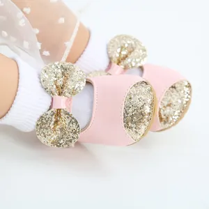 Detailed view of pink baby princess shoes with gold sequined bows and soft soles