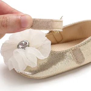 Close-up of golden baby princess shoe with velcro strap and white chiffon flower detail