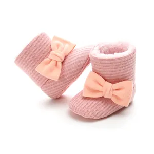 Detailed view of pink knitted baby snow boots with soft plush lining and peach bow