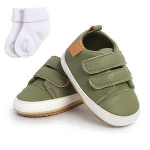 Olive green faux leather baby sneakers with white socks and adjustable velcro straps