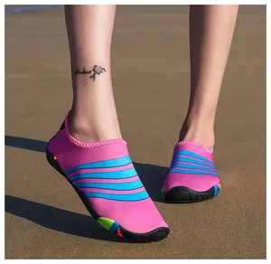 Gedetailleerd zicht op roze en blauw gestreepte waterschoenen op een zonnig zandstrand