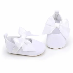 Zijaanzicht van witte babyprinsessenschoenen met grote satijnen strikken op witte achtergrond