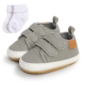 Detailed view of grey baby walking shoes with velcro straps and white cotton socks set.