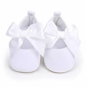 Detailweergave van witte baby prinsessenschoenen met grote satijnen strikken en zachte zolen
