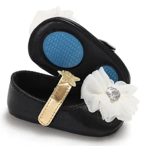 Detailed view of black baby girl princess shoes with white tulle flower and gold strap