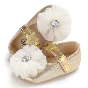 Detail shot of golden baby princess shoes with white mesh flower and rhinestones