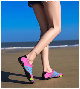 Zijaanzicht van roze en blauw gestreepte waterschoenen op een zonnige zandstrand achtergrond