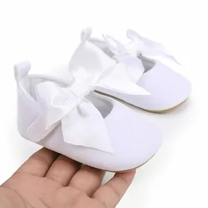 Detailweergave van elegante witte baby prinsessenschoenen met grote satijnen strikken erop