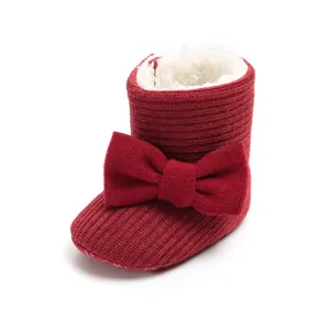 Macro view of red knitted baby snow boots featuring a plush lining and large bow