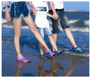 Familie die kleurrijke gestreepte sneldrogende waterschoenen draagt op een zonnig strand