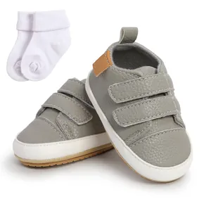 Grey toddler walking shoes featuring dual Velcro straps with a pair of white baby socks
