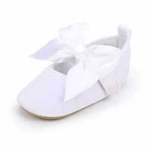Gedetailleerde weergave van witte baby prinsessenschoenen met een grote satijnen strikdecoratie