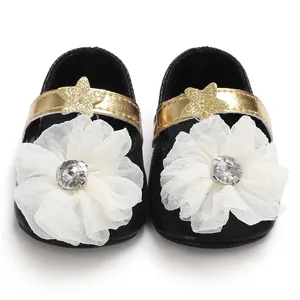 Detail shot of black baby princess shoes with white flower and gold star strap ornament