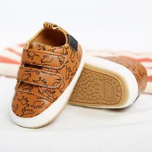 Close-up detail of brown baby walking shoes with dinosaur pattern and anti-slip sole