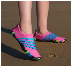 Close-up detail van lichtgewicht roze en blauwe blote voeten waterschoenen op zand