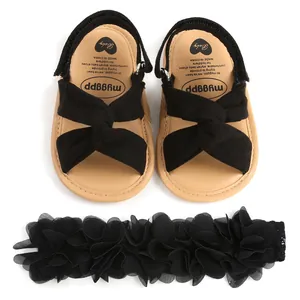 Vista detallada del conjunto de sandalias negras para bebé y diadema de flor a juego