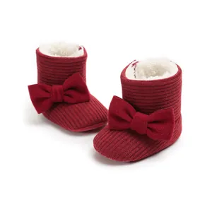 Close-up of red fleece-lined baby boots with a large bow and soft white inner lining