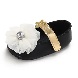 Close-up of black baby princess shoes with white tulle flower and gold star strap.