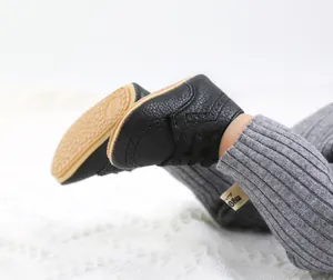 Close-up of black PU leather baby shoes with soft non-slip soles on a white rug