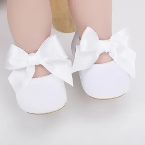 Gedetailleerd overzicht van witte baby prinsessenschoenen met grote satijnen strikken