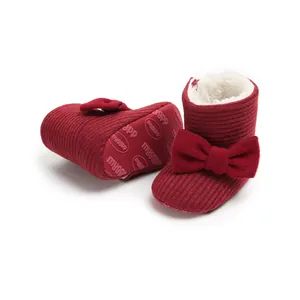 Detailed view of red knitted baby snow boots featuring a bow and warm plush lining