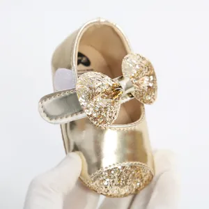 Detailed macro view of shiny gold baby princess shoes with sequin bow and soft sole