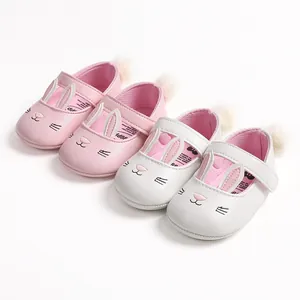 Detail view of pink and white baby walking shoes with cute rabbit design and pom-poms.