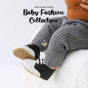 Close-up of black and white baby PU walking shoes with gray ribbed leggings