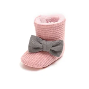 Close-up detail of pink knitted baby winter boots with soft fur lining and bow